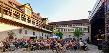 Es ist das Publikum der Schlosshofkonzerte vom letzten Jahr zu sehen, die seitlich, zur Bühne schauend, fotografiert wurden.