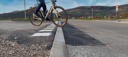 Eine Person auf einem Fahrrad fährt über den abgesenkten Bordstein.