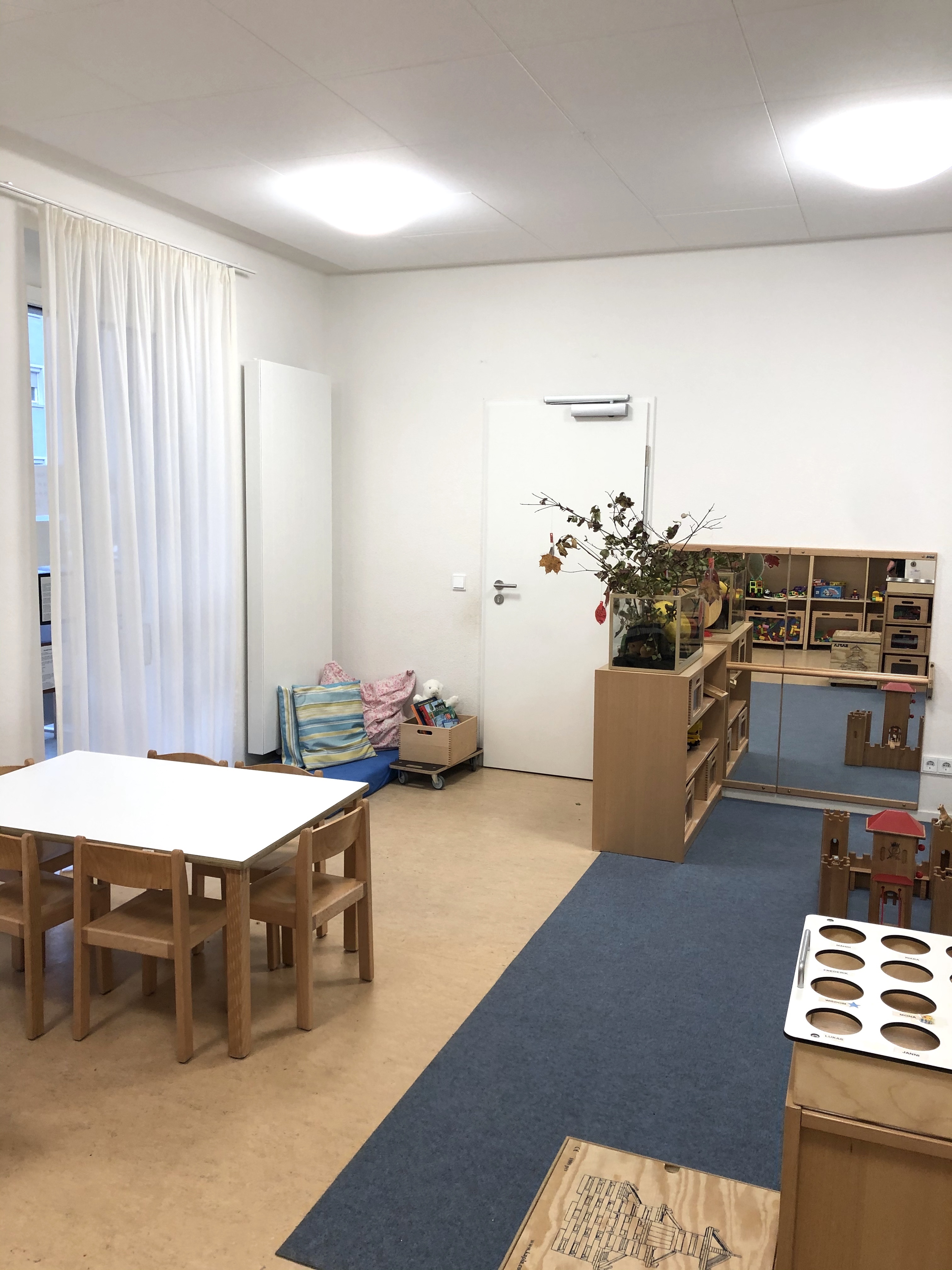 Das Bild zeigt das Bauzimmer im Kindergarten aus einer anderen Perspektive. Hier sehen wir einen Tisch und ein Regal auf der anderen Seite des Raumes.