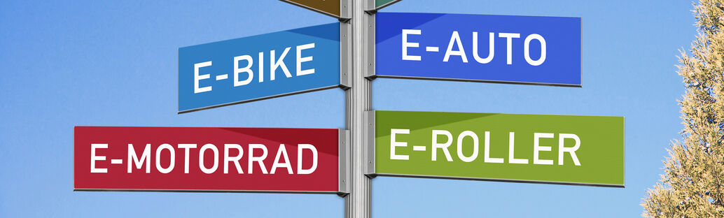 Wegweiser mit verschiedenen Aufschriften (E-Bike, E-Auto, E-Roller, E-Motorrad)