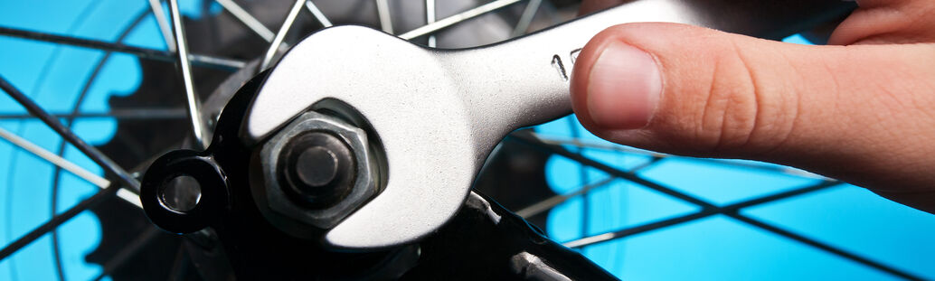 Speichen eines Fahrrads, Hand hält Doppelmaulschlüssel davor