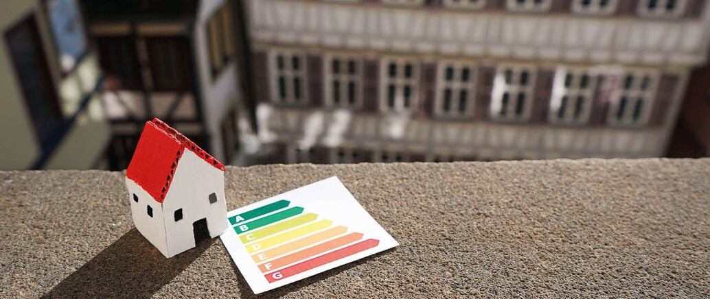 Gebasteltes Haus steht in der Tübinger Altstadt auf einer Mauer, daneben eine Energie-Skala.