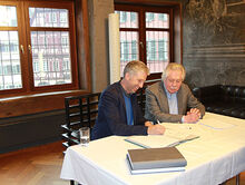 Oberbürgermeister Boris Palmer und der Präsident der Hölderlin-Gesellschaft, Professor Dr. Johann Kreuzer, setzen ihre Unterschriften unter den Schenkungsvertrag.