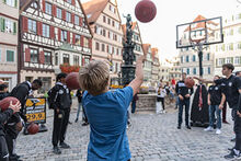 Kind wirft auf dem Marktplatz einen Basketball 